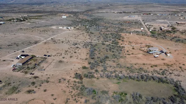 a view of a dry field with trees in the background