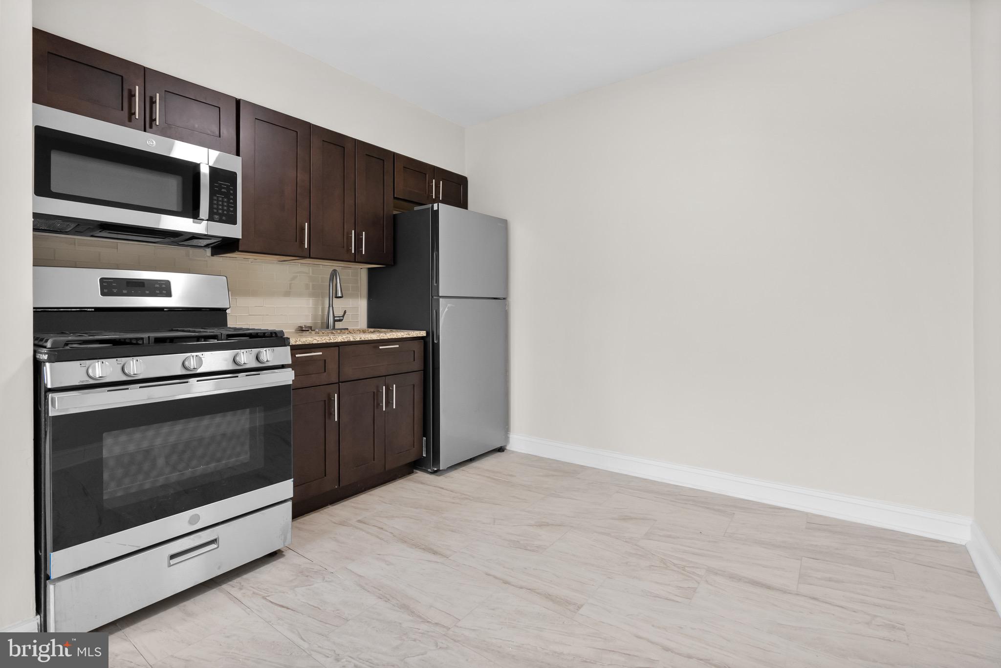 5156 D Street, Unit 2 Philadelphia, PA 19120 - Photo 6 of 23 a kitchen with stainless steel appliances a stove a microwave and white cabinets
