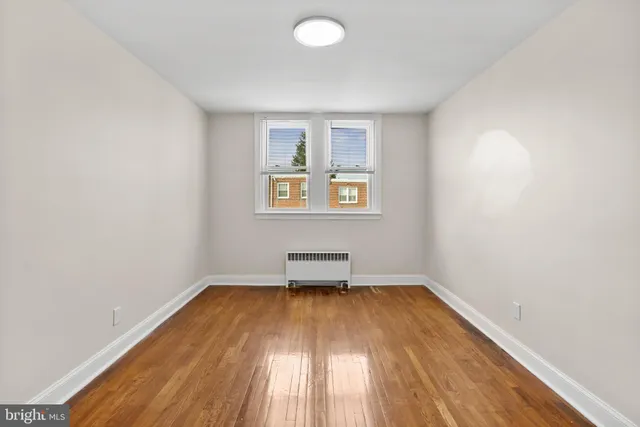 an empty room with a hardwood and windows
