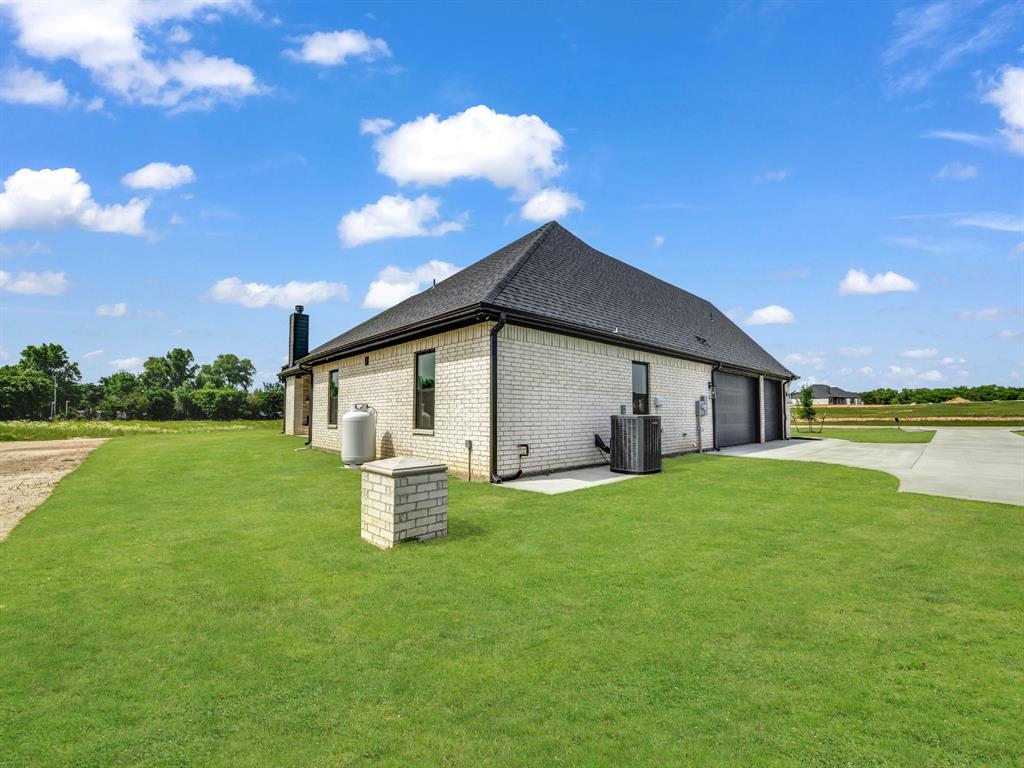 143 Desperado Way Weatherford, TX 76088 - Photo 5 of 36 View of property exterior with driveway, central AC unit, a garage, a lawn, and brick siding