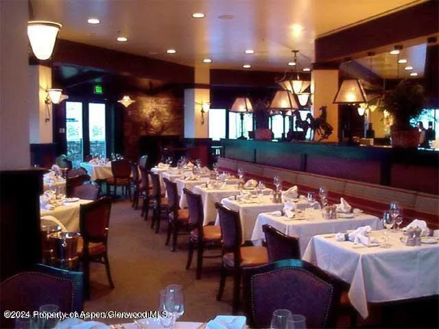 a dining hall with furniture a rug and white walls