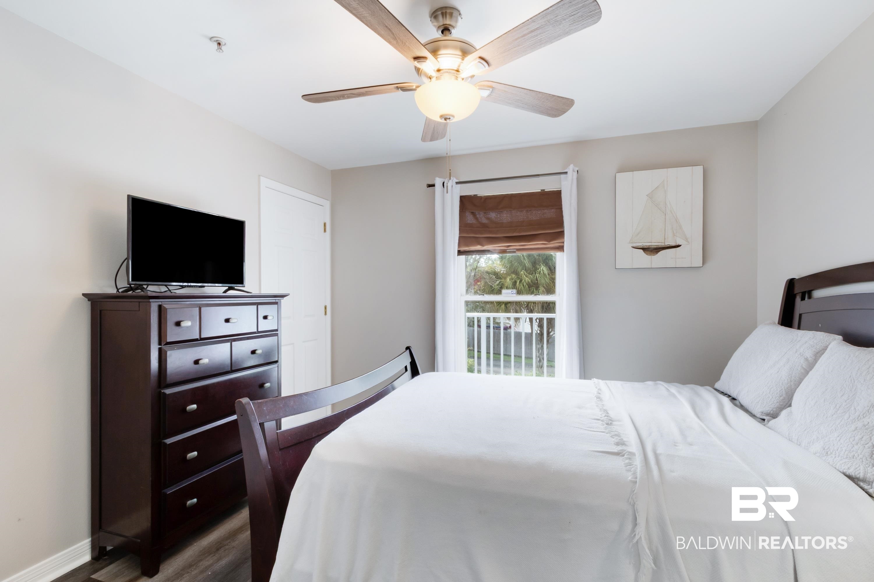 25957 Canal Road, Unit 208 Orange Beach, AL 36561 - Photo 15 of 28 Light-filled bedroom featuring a ceiling fan, a window with white blinds and brown shades, and wood-finish flooring