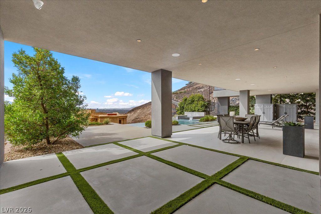 657 Ridgestone Rim Court Henderson, NV 89012 - Photo 91 of 97 Concrete pavers embedded with turf lead to a sheltered outdoor living area framing desert vistas.