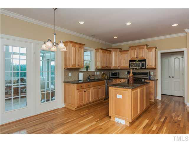 5820 Turner Store Lane Raleigh, NC 27603 - Photo 10 of 25 Breakfast area includes hardwoods, crown molding and drop nickel finish chandelier. Leads out to sunroom with great private views.