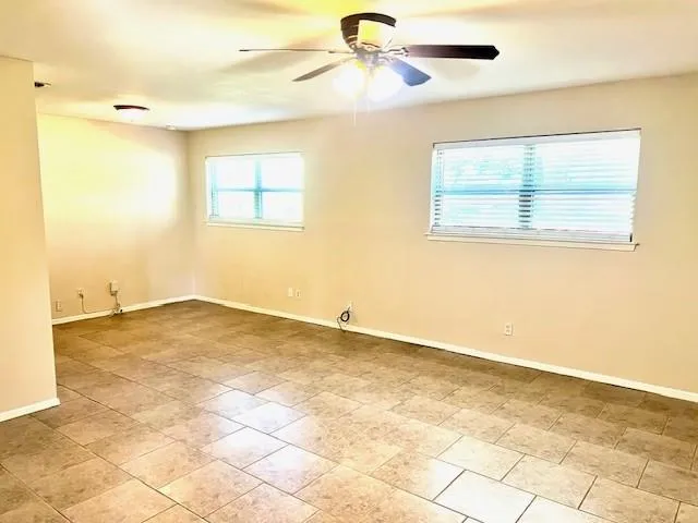 an empty room with a window and a ceiling fan