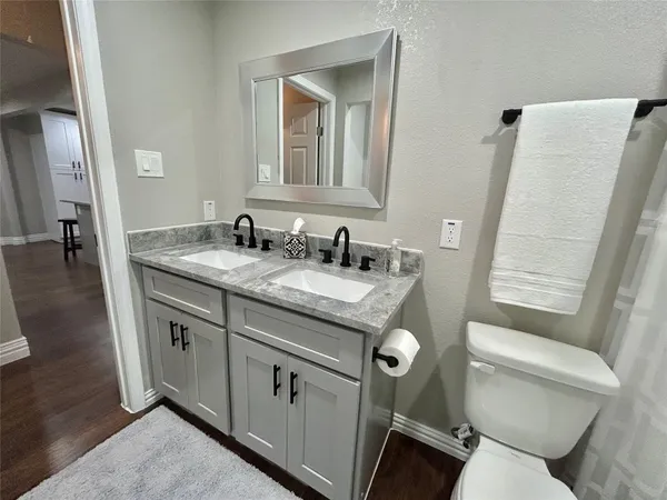 a bathroom with a granite countertop toilet sink and mirror
