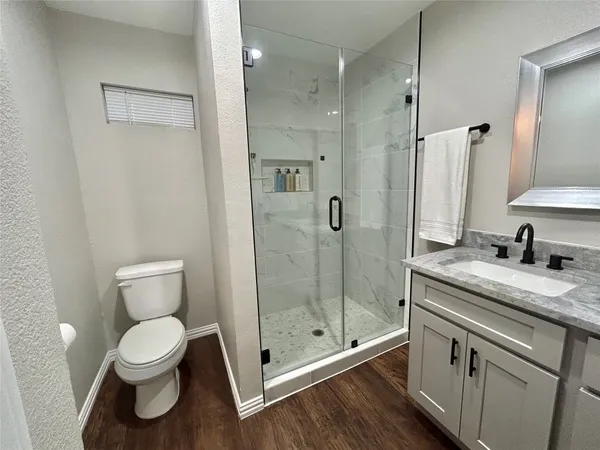 a bathroom with a granite countertop sink a toilet and a shower