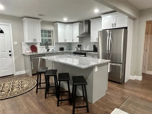 a kitchen with stainless steel appliances granite countertop a table chairs sink refrigerator and cabinets