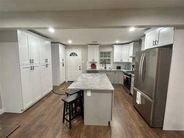 a kitchen with refrigerator a sink and wooden floor