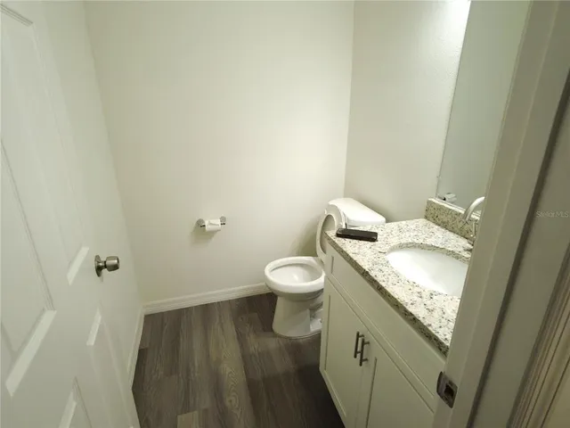 a bathroom with a granite countertop toilet and a sink