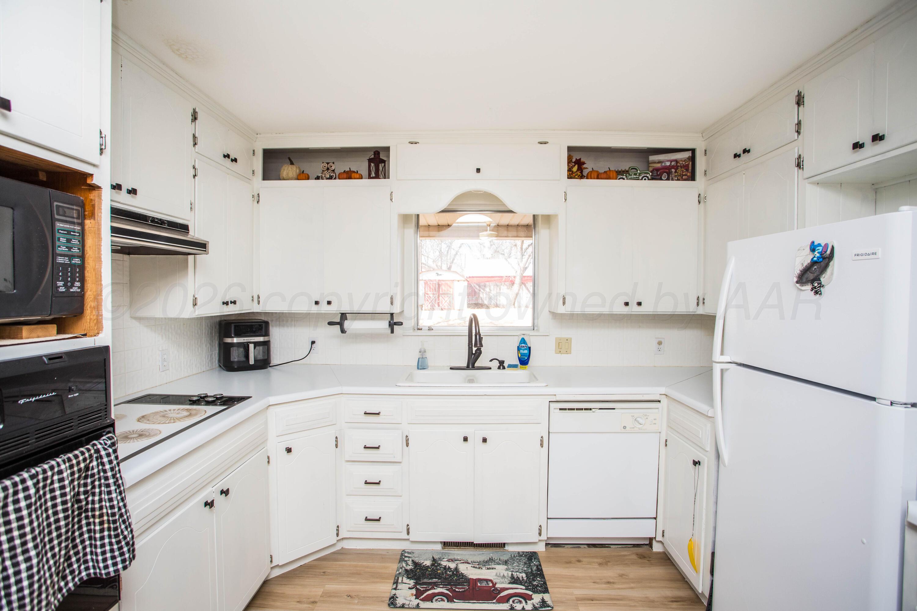 73 Houston Road Tulia, TX 79088 - Photo 18 of 55 a kitchen with granite countertop a refrigerator sink stove and white cabinets