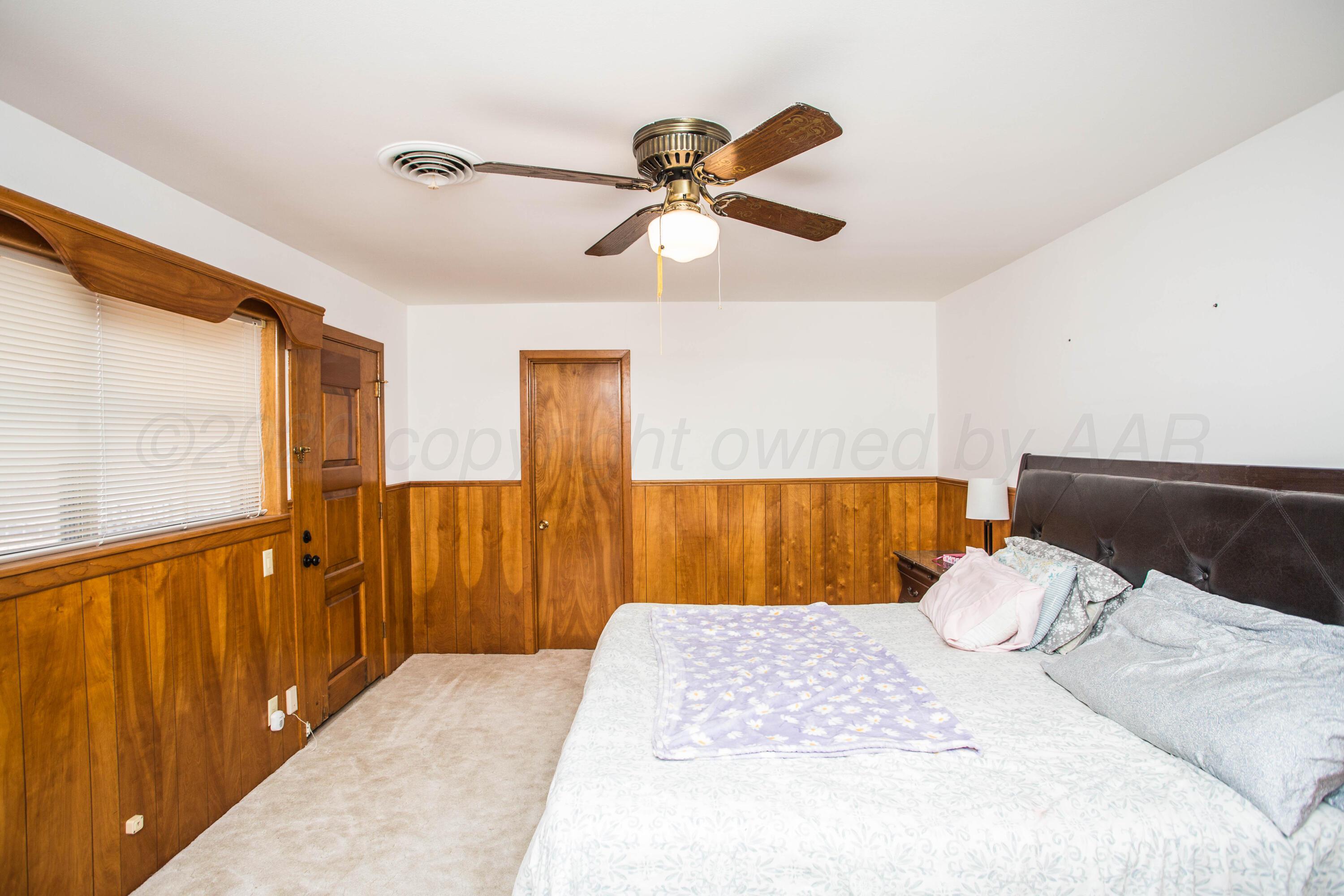 73 Houston Road Tulia, TX 79088 - Photo 37 of 55 a bedroom with a large bed and a chandelier