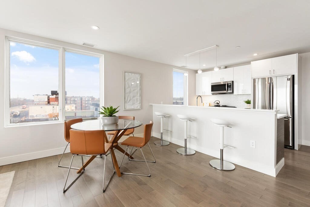 398 Cambridge Street, Unit 502 Boston, MA 02134 - Photo 1 of 11 a kitchen with stainless steel appliances a dining table chairs refrigerator and sink