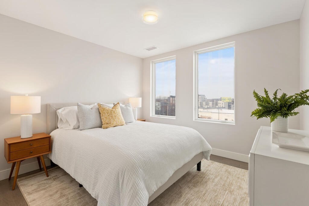 398 Cambridge Street, Unit 502 Boston, MA 02134 - Photo 7 of 11 a bedroom with a bed table and a window