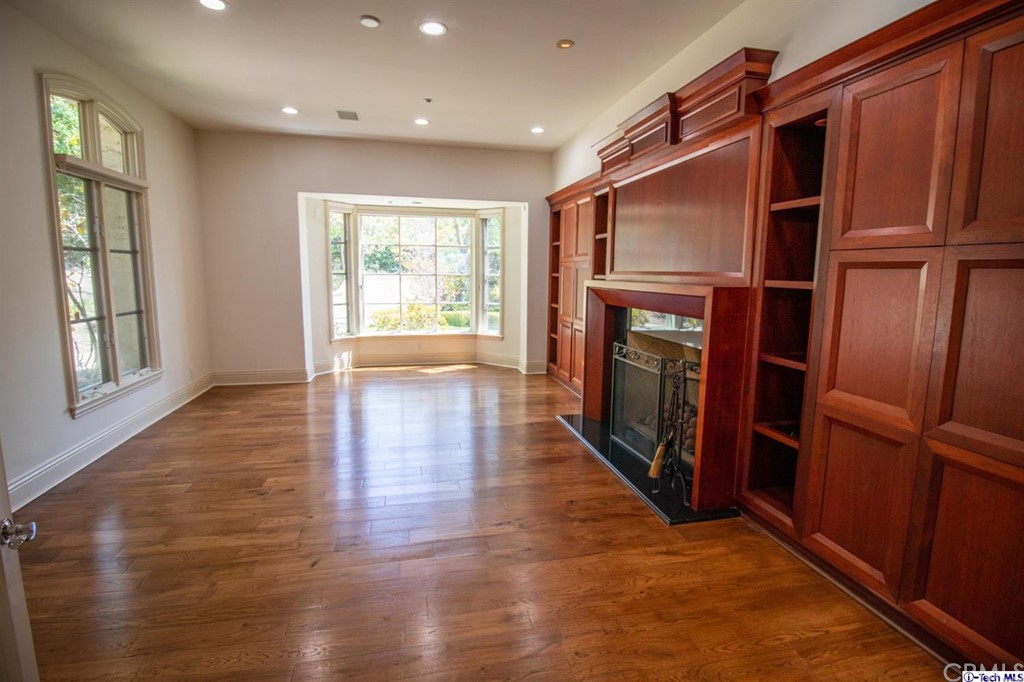 12801 Chalon Road Los Angeles, CA 90049 - Photo 14 of 77 an empty room with wooden floor fireplace and windows