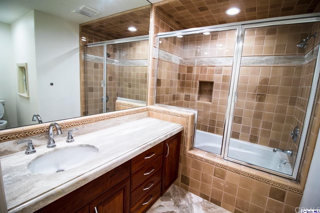 12801 Chalon Road Los Angeles, CA 90049 - Photo 52 of 77 a bathroom with a shower sink and mirror