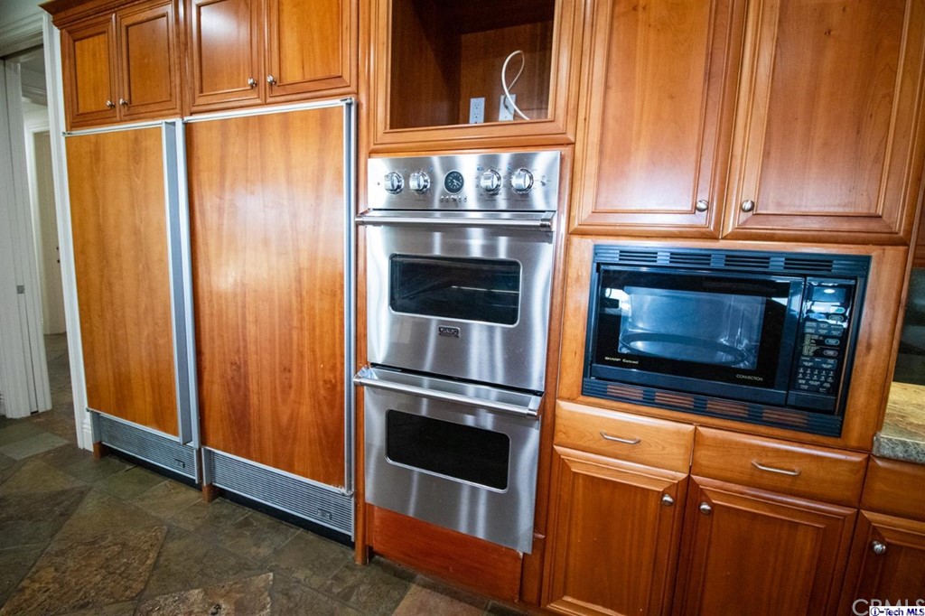 12801 Chalon Road Los Angeles, CA 90049 - Photo 9 of 77 a kitchen with granite countertop white cabinets and stainless steel appliances
