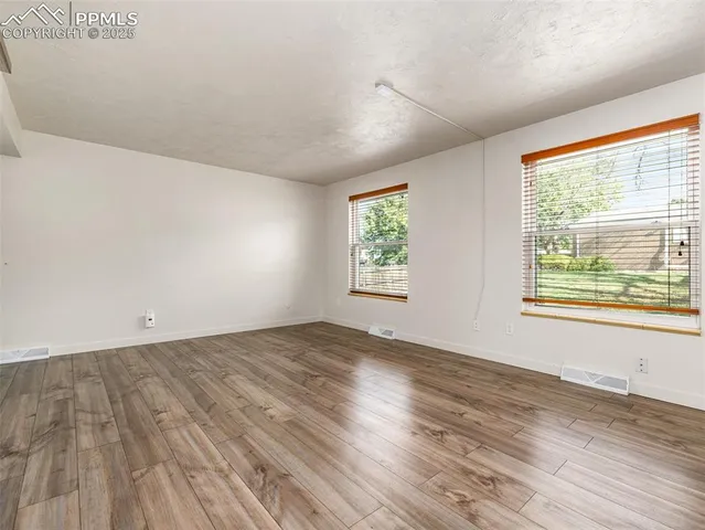 an empty room with wooden floor and windows