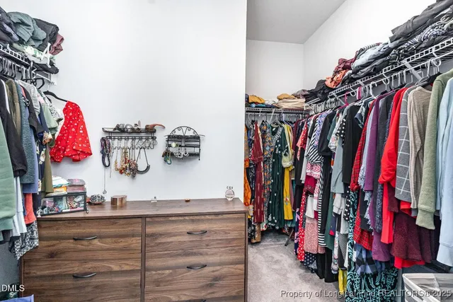 a view of walk in closet with clothes and shoes