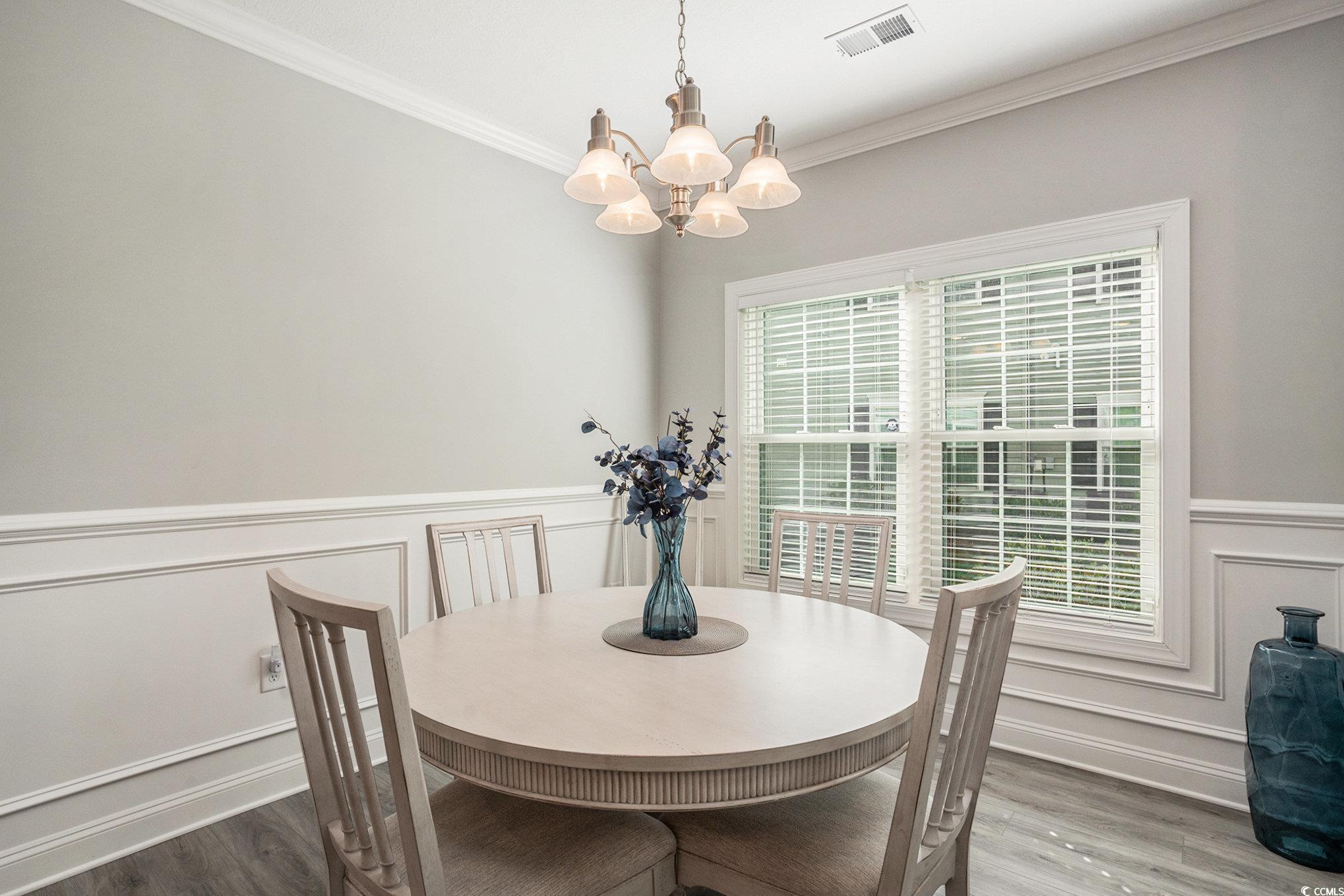 932 Jackline Place, Unit 101 Murrells Inlet, SC 29576 - Photo 14 of 40 Dining area with a wainscoted wall, a decorative wall, ornamental molding, wood finished floors, and a chandelier