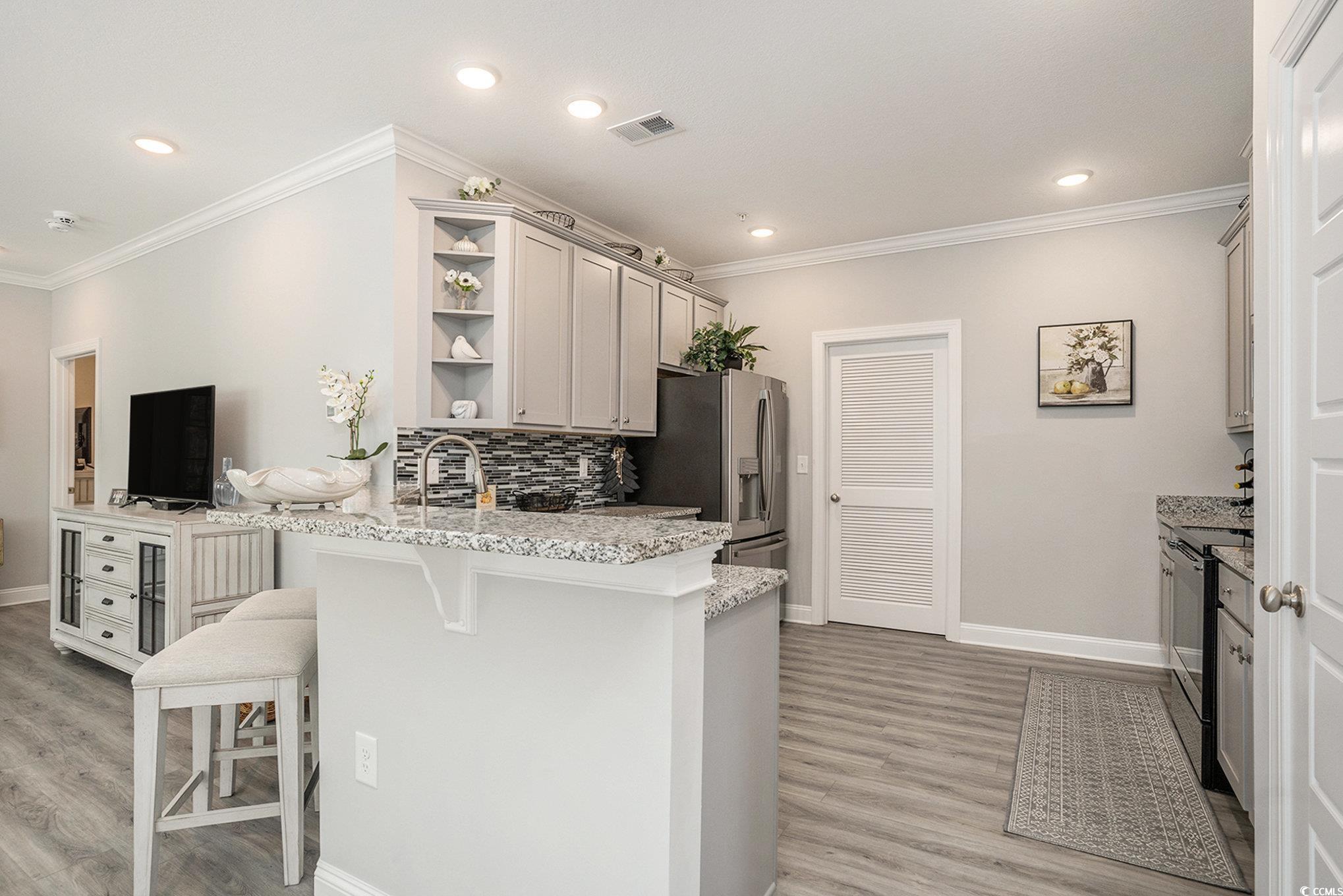 932 Jackline Place, Unit 101 Murrells Inlet, SC 29576 - Photo 15 of 40 Kitchen featuring a breakfast bar, ornamental molding, light stone countertops, black electric range oven, and gray cabinets