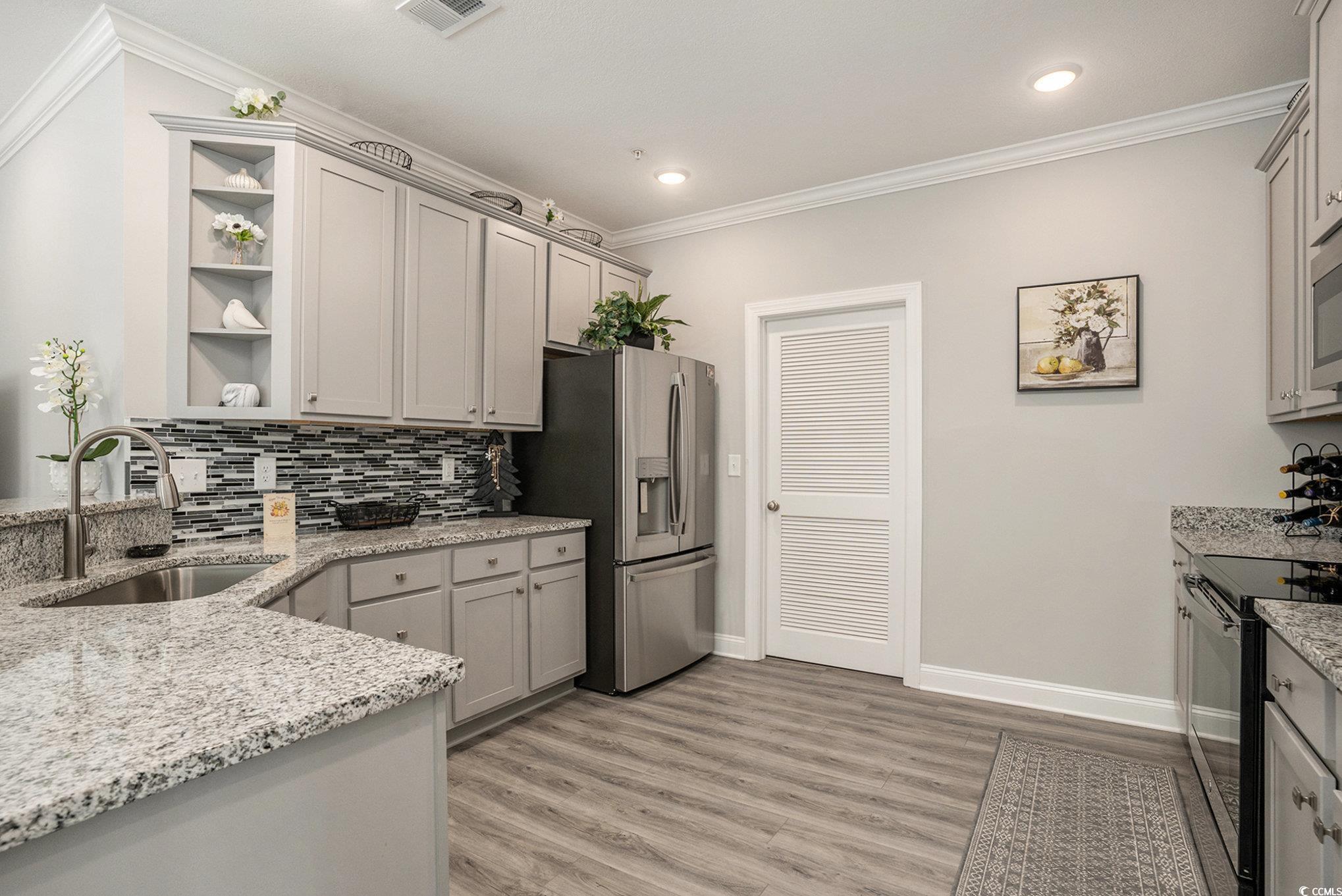 932 Jackline Place, Unit 101 Murrells Inlet, SC 29576 - Photo 16 of 40 Kitchen with open shelves, ornamental molding, light stone counters, stainless steel appliances, and light wood-style flooring