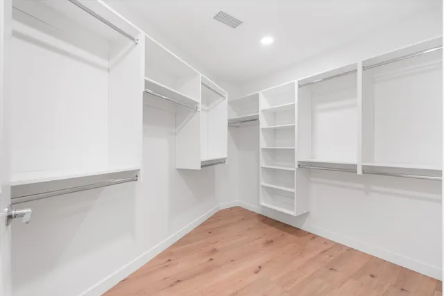 an empty room with wooden floor & closet and kitchen space