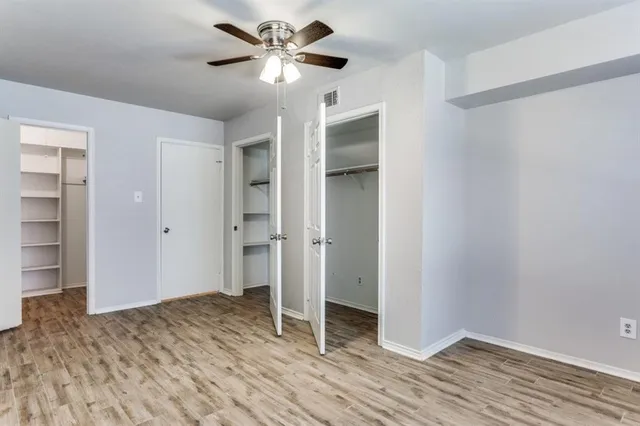 a view of empty room with wooden floor and ceiling fan