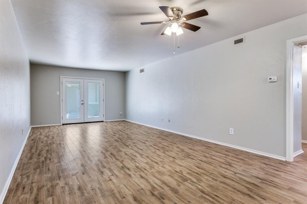 4022 Ridglea Country Club Drive, Unit 608 Fort Worth, TX 76126 - Photo 4 of 28 an empty room with wooden floor fan and windows