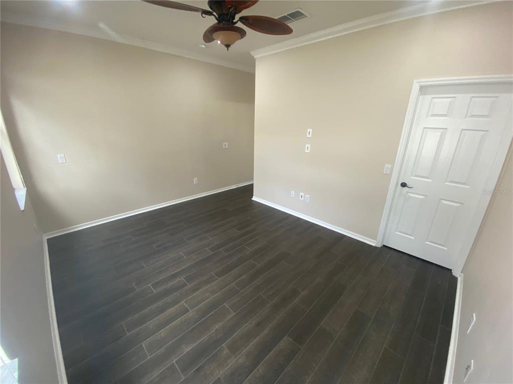 2409 Spring Hollow Loop Wesley Chapel, FL 33544 - Photo 21 of 47 an empty room with wooden floor cabinet and windows
