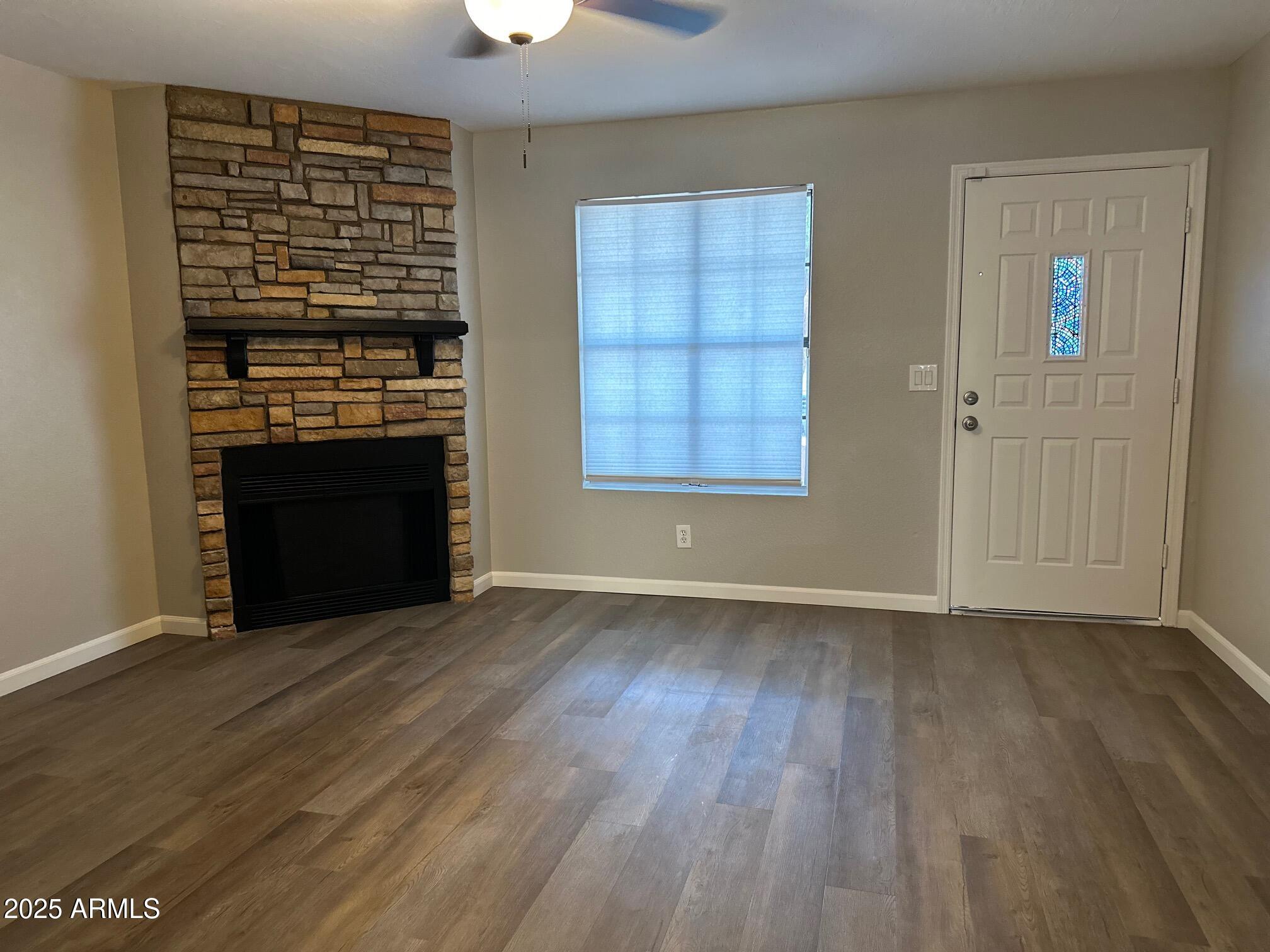 3491 North Arizona Avenue, Unit 20 Chandler, AZ 85225 - Photo 4 of 13 an empty room with wooden floor a fireplace and windows