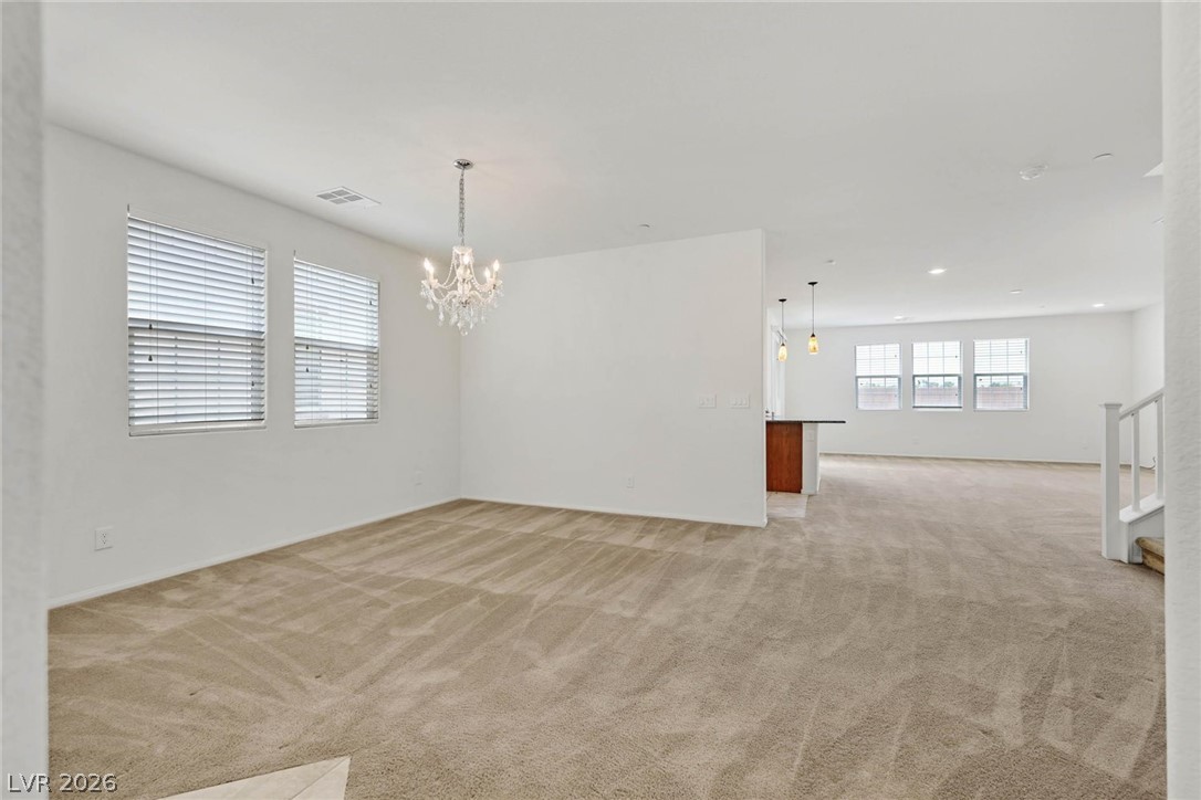 155 Fulgora Street Henderson, NV 89074 - Photo 3 of 30 A well-lit, open-concept living area with plush carpet and a stylish chandelier.