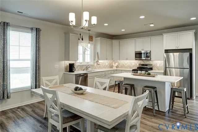 a kitchen with kitchen island a dining table chairs and refrigerator