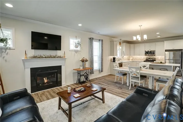 a living room with stainless steel appliances furniture a fireplace and a open kitchen view