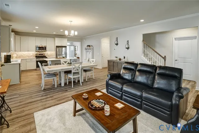 a living room with furniture a wooden floor and kitchen view