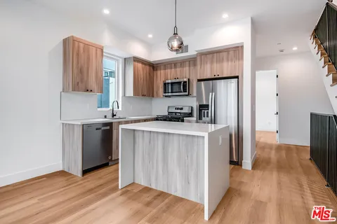 a kitchen with kitchen island a refrigerator stove a sink and a oven with wooden floor