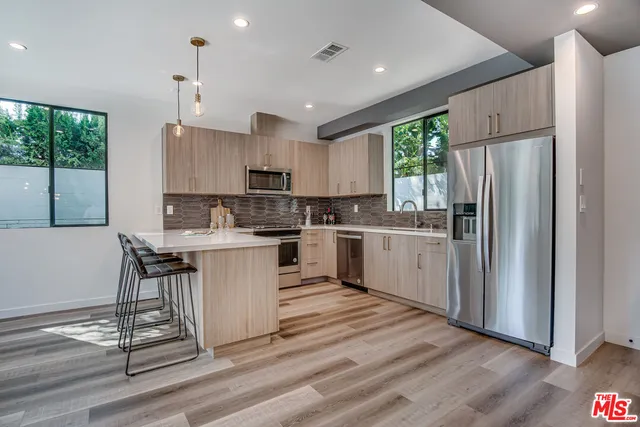 a kitchen with a refrigerator a sink and white cabinets