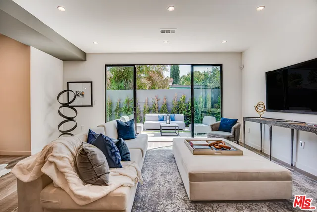 a living room with furniture a flat screen tv and a floor to ceiling window