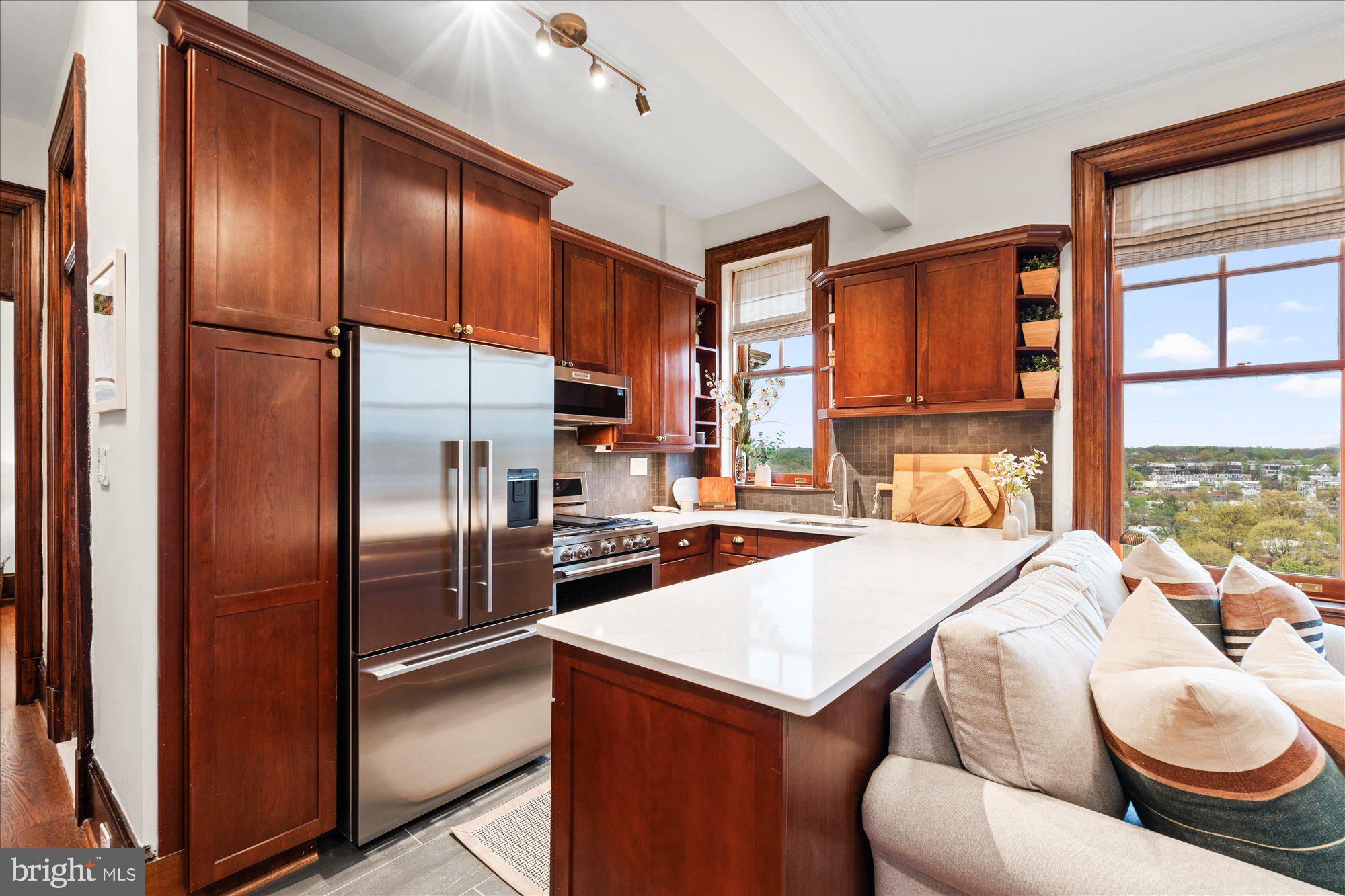 2853 Ontario Road Northwest, Unit 609 Washington, DC 20009 - Photo 6 of 14 a kitchen with stainless steel appliances granite countertop a refrigerator a sink dishwasher with a dining table and chairs with wooden floor