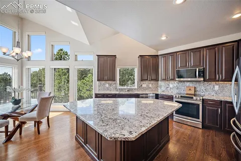 a kitchen with granite countertop center island wooden floor and stainless steel appliances