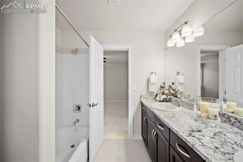 a bathroom with a granite countertop sink a large mirror and a shower