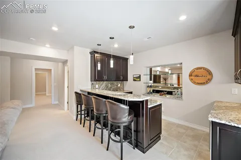 a kitchen with stainless steel appliances granite countertop a stove top oven a sink a dining table and chairs