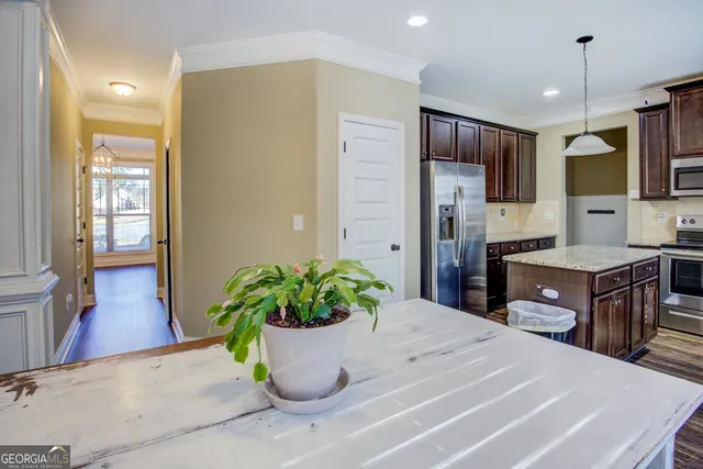 a kitchen with stainless steel appliances kitchen island granite countertop a refrigerator a stove a sink with wooden cabinets and floor