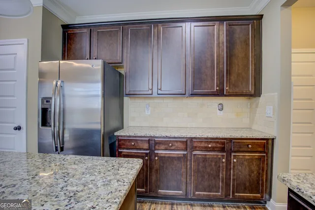 a kitchen with granite countertop a refrigerator and wooden cabinets