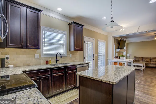 a kitchen with granite countertop stainless steel appliances a sink stove and cabinets