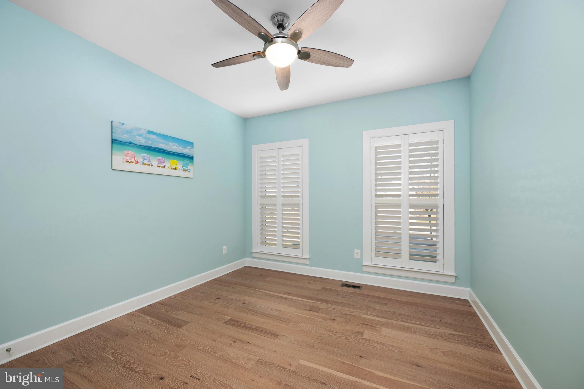 33415 Bridgehampton Lane Lewes, DE 19958 - Photo 21 of 66 an empty room with wooden floor chandelier fan and windows
