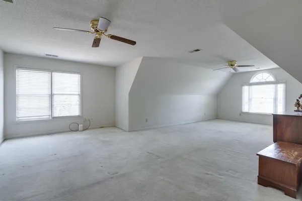 an empty room with windows and fan