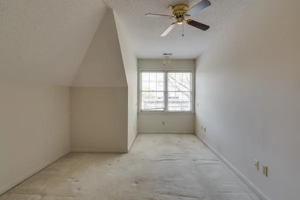 an empty room with chandelier fan and windows