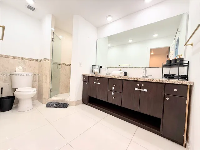 a spacious bathroom with a granite countertop sink a toilet and a mirror