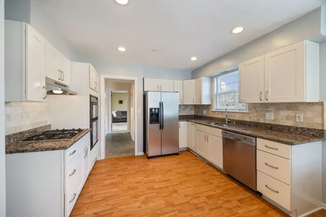 a large kitchen with stainless steel appliances granite countertop a stove and a refrigerator
